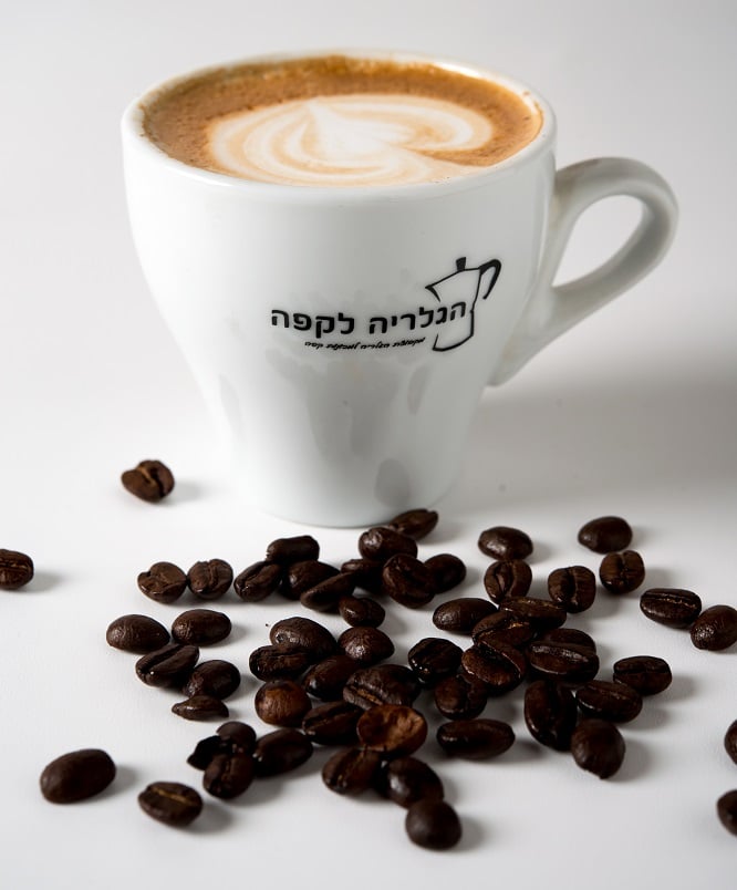 כוס קפה מעוצבת לצד פולי קפה